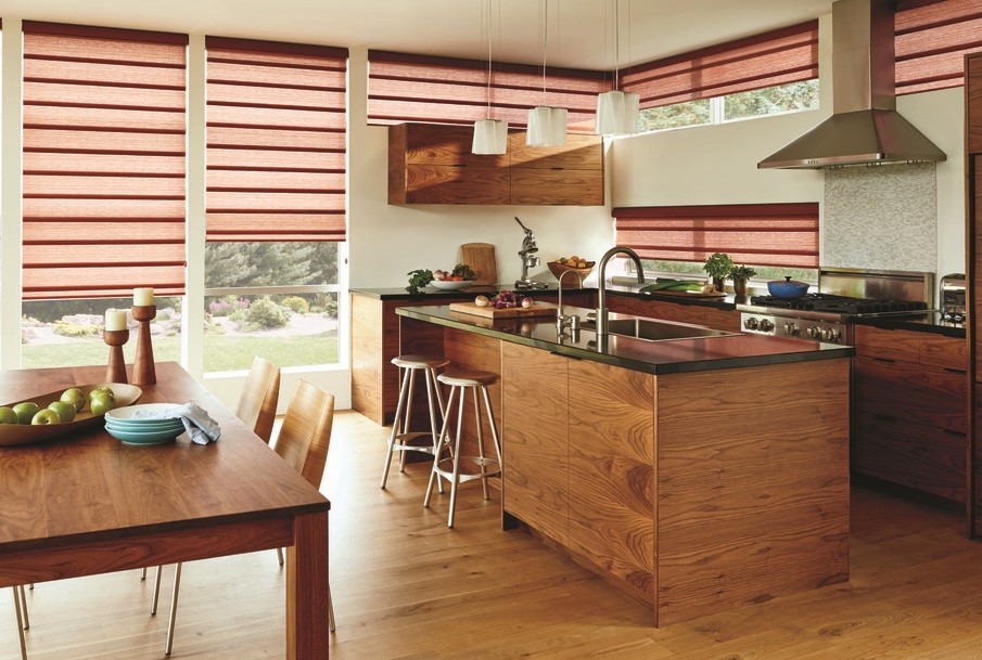 Kitchen with hardwood cabinets and a wooden dining table with burgundy Hunter Douglas pleated shades on the windows. 