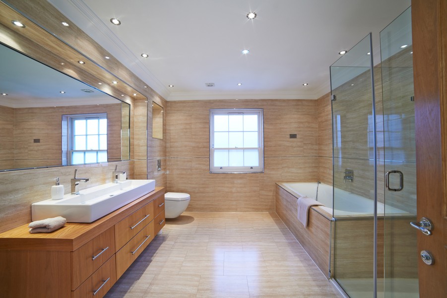 Well-lit bathroom featuring wooden cabinets and walls with a walk-in shower and standalone tub. 