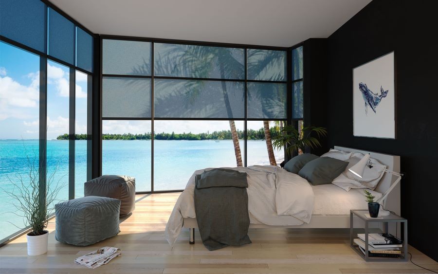 A bedroom with shades partially lowered, looking out over the ocean.