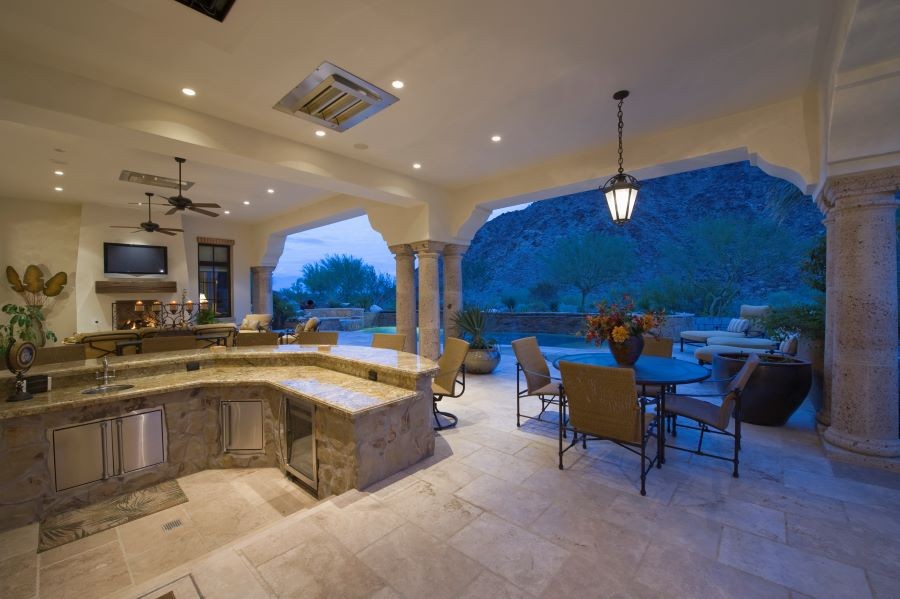 An open-air concept with an outdoor kitchen and entertainment area with a TV and in-ceiling speakers.