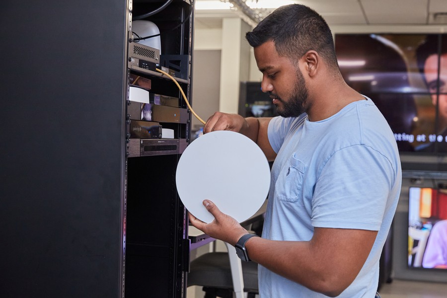 Engineer connecting an in-ceiling speaker to an AV rack to test it.