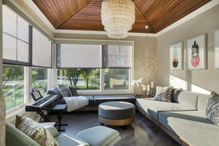 Motorized shades lowered halfway across windows in a sunroom. 