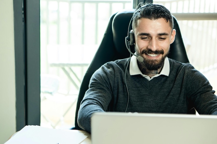 A remote technician at a computer wearing a headset.