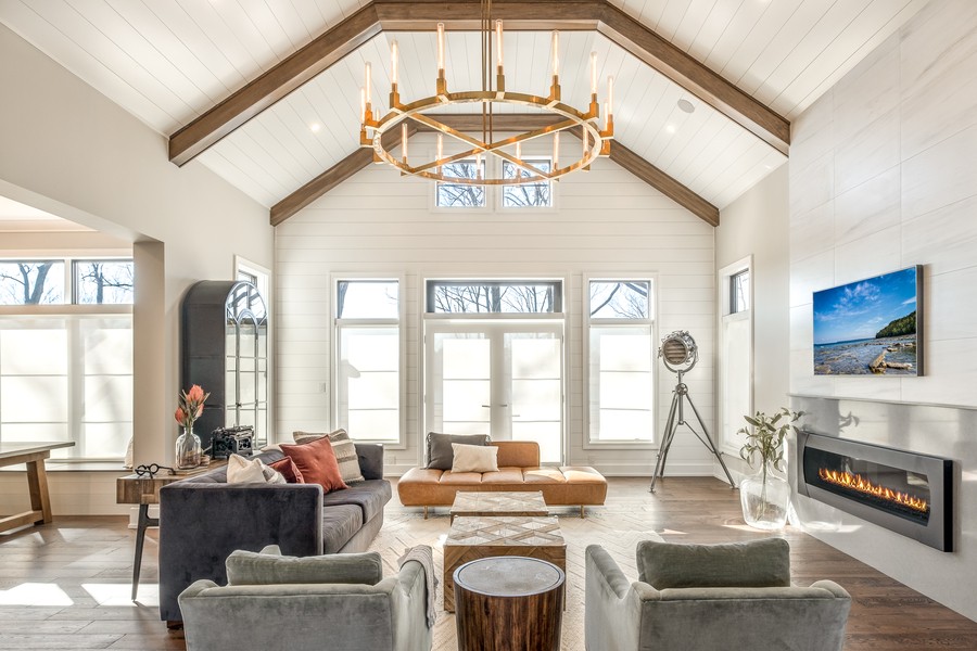 A living area filled with natural light. Shades are drawn over the windows and a picture hangs above the fireplace.